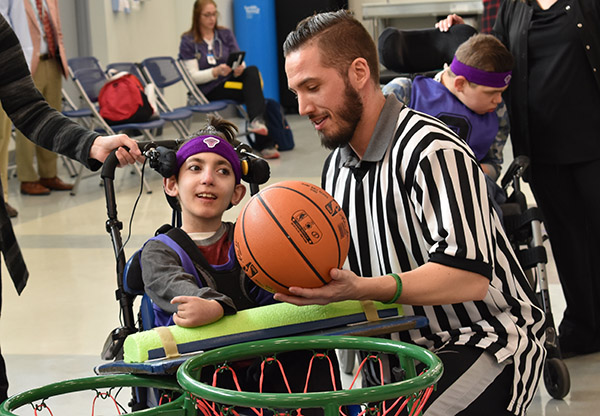 male staff member referee working with young boy with disabilities in a wheelchair