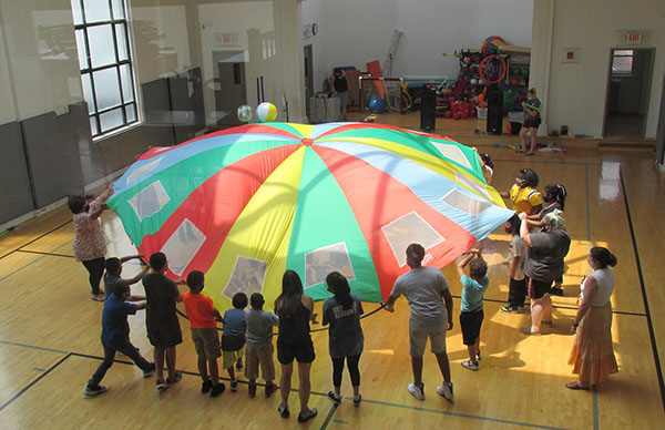 North Hudson Academy students playing with parachute and ball in gym/physical ed activity